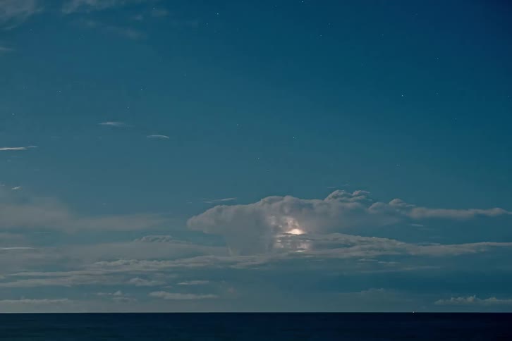 Lightning illuminating a cloud over the sea