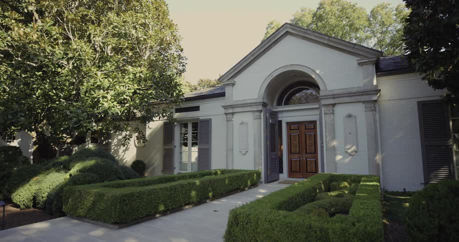 The front of a residential building with a garden on the lawn at midday