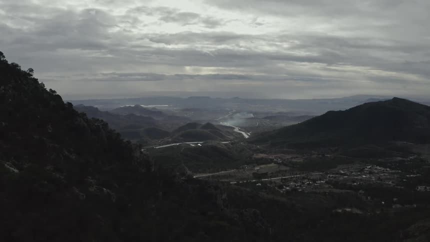 Forested mountains tower over a town on an overcast day