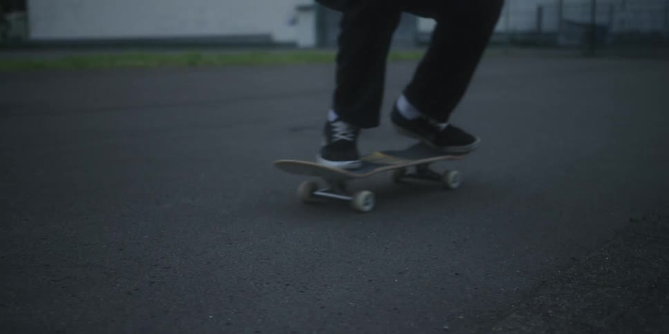 A person riding a skateboard performs a kick flip without falling