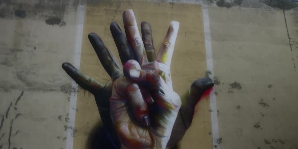 Mural of intertwined hands painted on a large exterior wall