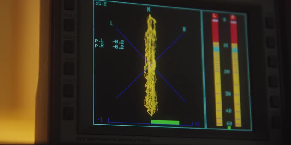 Closeup of a monitor displaying moving yellow signals on an audio vectorscope