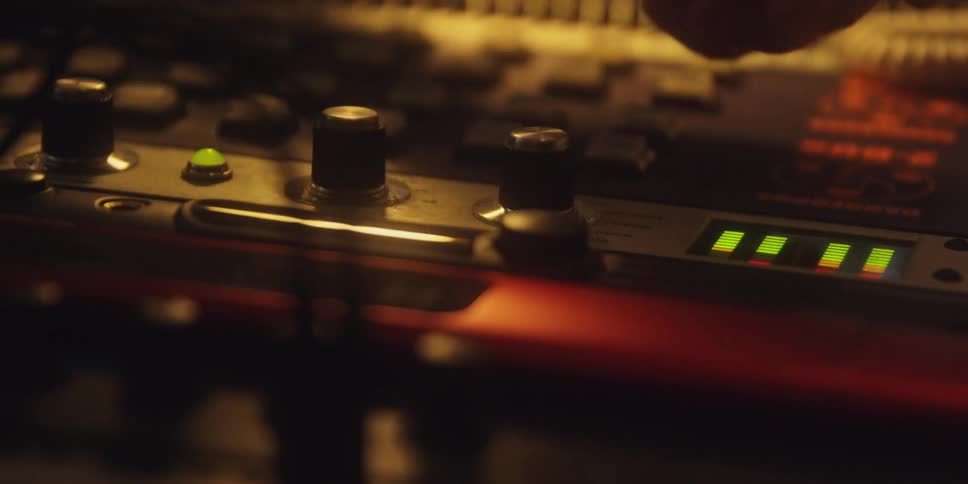 A hand in a dim lit area adjusting knobs on a sounding board