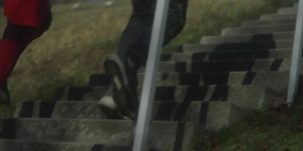 Two males quickly run up a set of concrete stairs while exercising