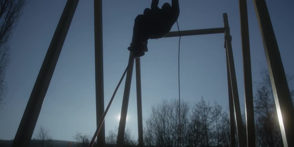 A person climbs up a rope as part of an obstacle course