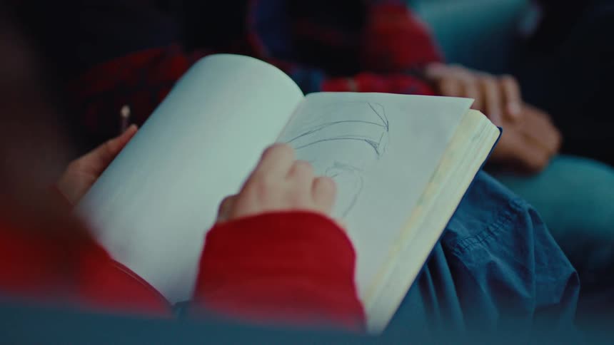 Young woman drawing in book with pencil