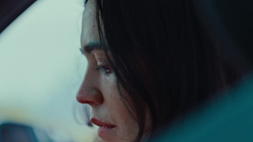 Young adult woman sitting inside of a car looking back and forth between her front and her side with a contemplative facial expression during day time