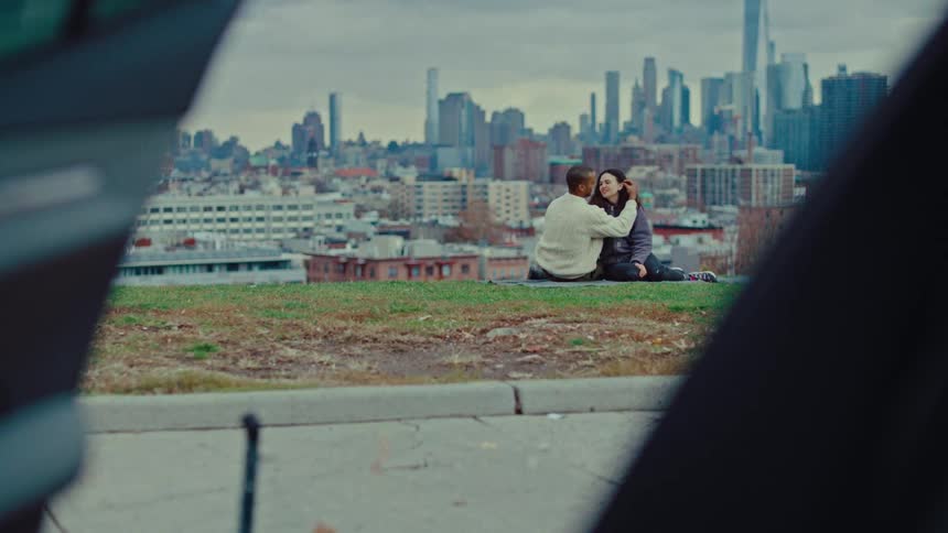 A man and woman sitting outdoors near a city