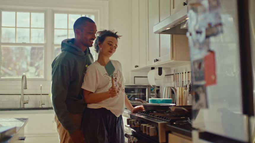 Two partners conversing romantically while cooking together in the kitchen during daytime