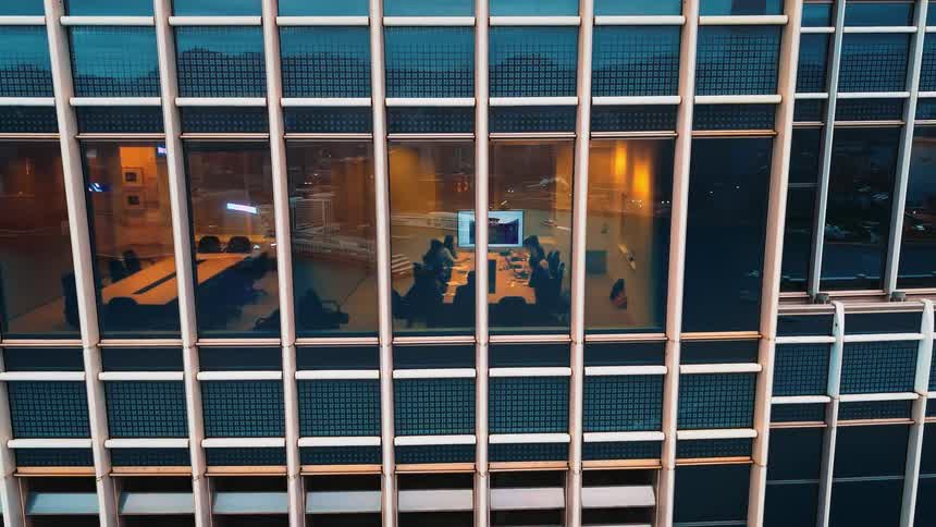 Lit conference room at a modern building with reflected urban view