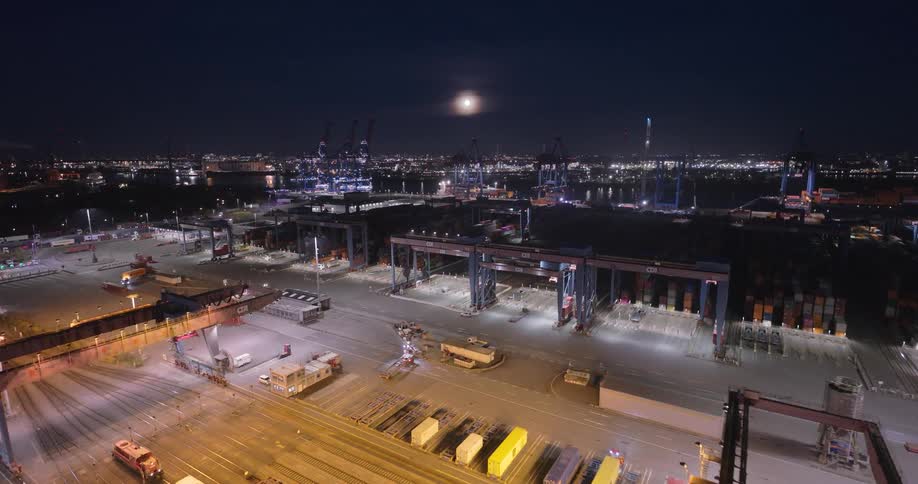Illuminated port at night with cranes and containers under the full moon