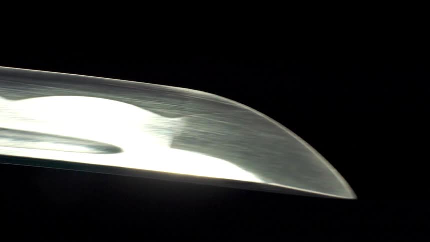 Katana blade in closeup with light reflection highlighting the edge
