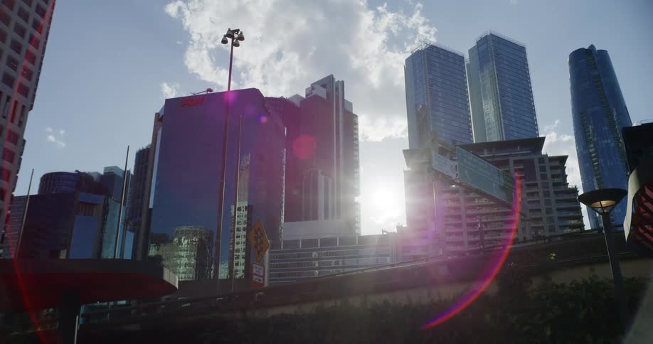Cluster of tall buildings reflecting sunlight with lens flare in the frame