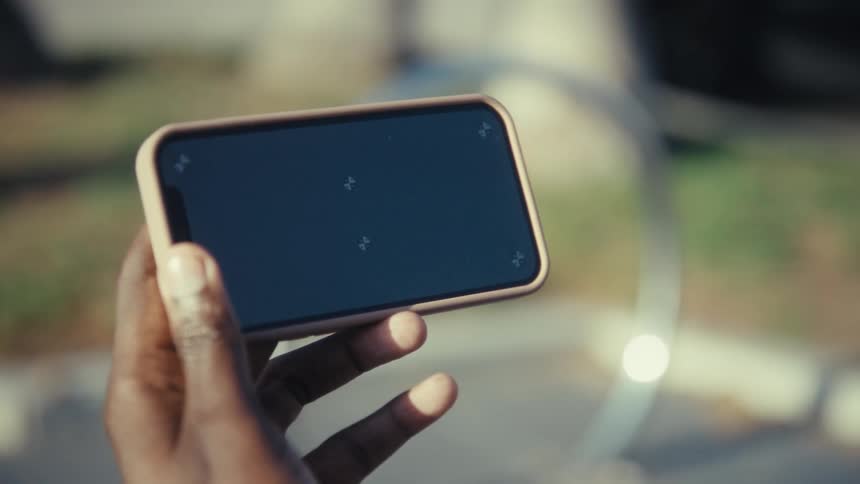 A persons hand holds a smartphone with a blank screen displaying small placement markers