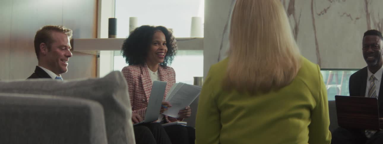 Group of professionals talking in a corporate setting with documents and tablets