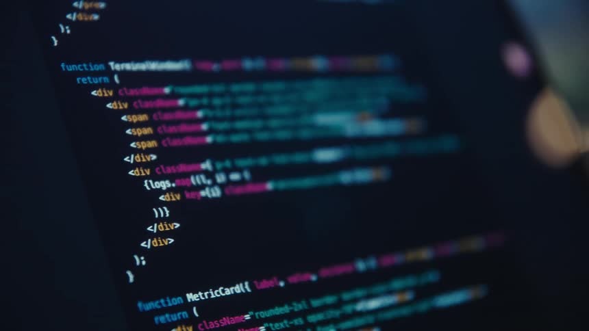 Coding text on a computer screen as a woman types on the keyboard