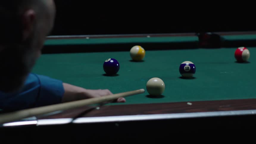 A black man is playing in a billiard game