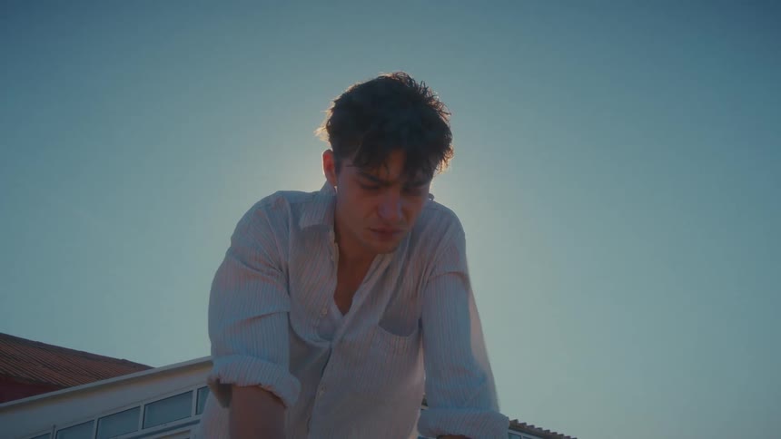 A man standing outdoors with the wind blowing on his clothes