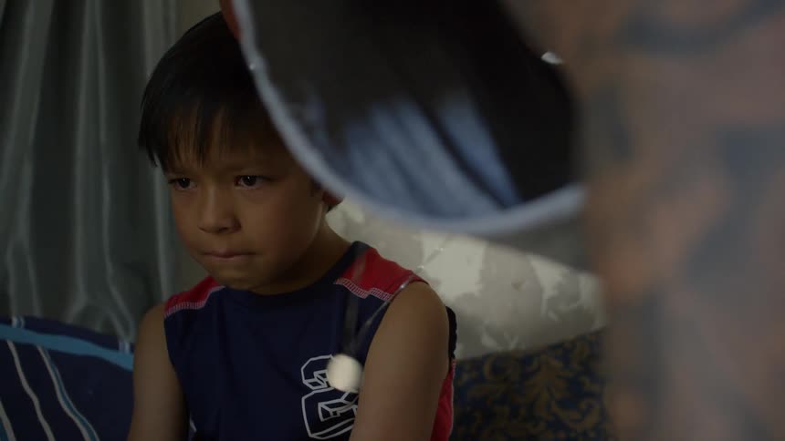 A child sitting on a couch while someone else is moving around