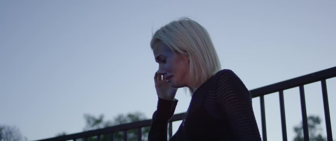 A woman is upset and crying as she stands outside