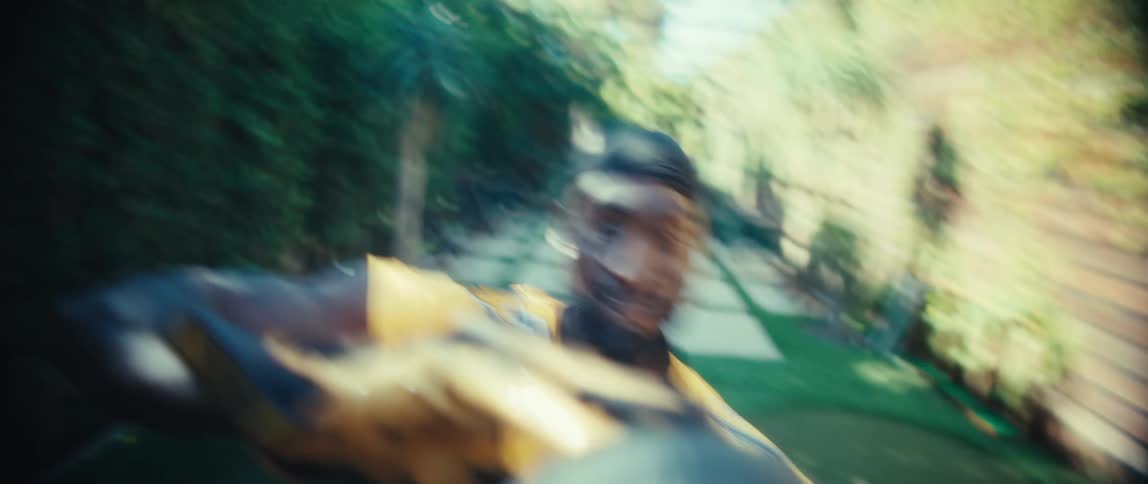 An american football player catches a football in a backyard while wearing a yellow jersey at midday