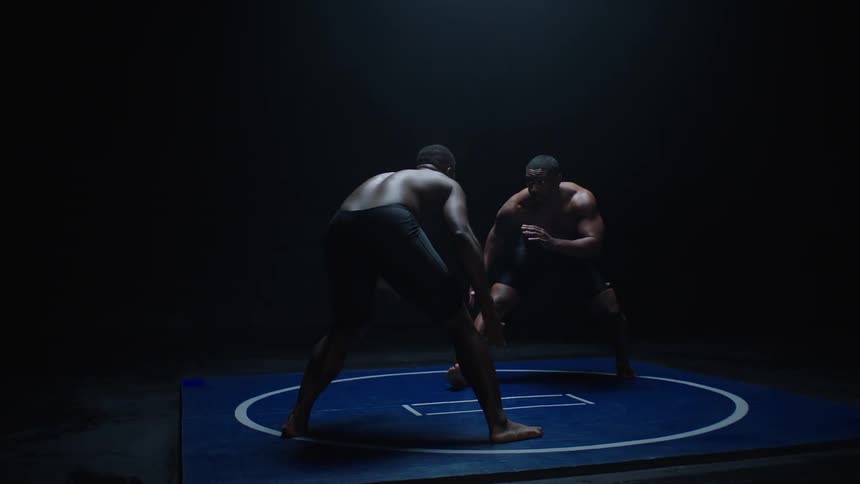 Two wrestlers cautiously move in the ring as they make contact