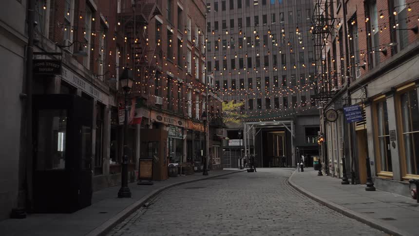 Pedestrians walk along a city street decorated with strings of light during the daytime