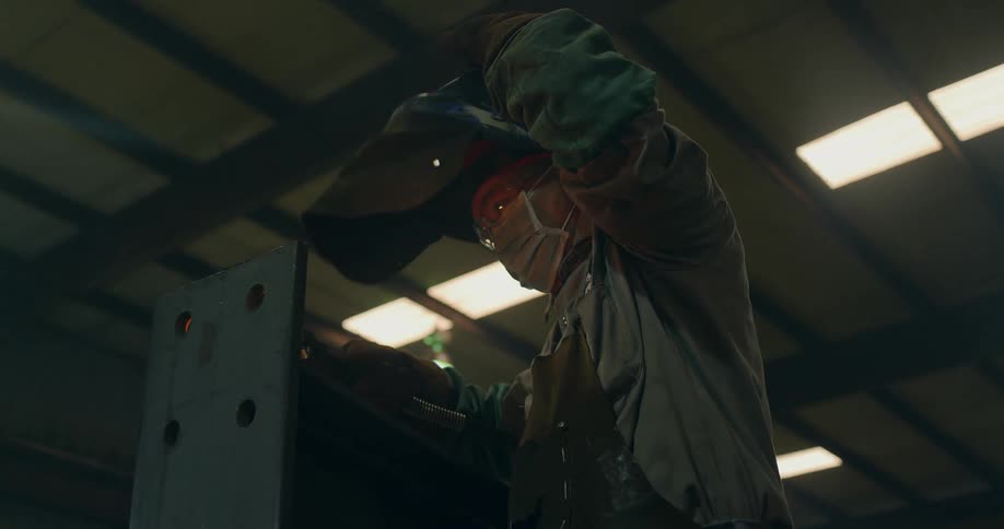 A man is welding in a warehouse