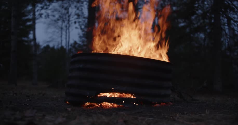 A view of a campfire burning in the forest at night
