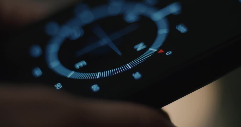 Human hands using a smartphone and opening an app that shows a compass indoors