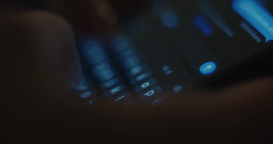 Persons fingers pressing letters on the keypad of their smart phone