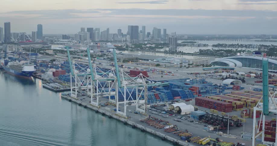 Several large cranes for moving cargo containers are lined up at a shipyard