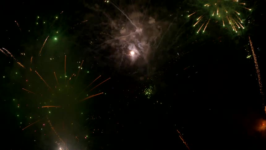 The video captures a dynamic fireworks display at night featuring multiple bursts and streamers of light the colorful pyrotechnics illuminate the dark sky with shades of red green and goldenorange
