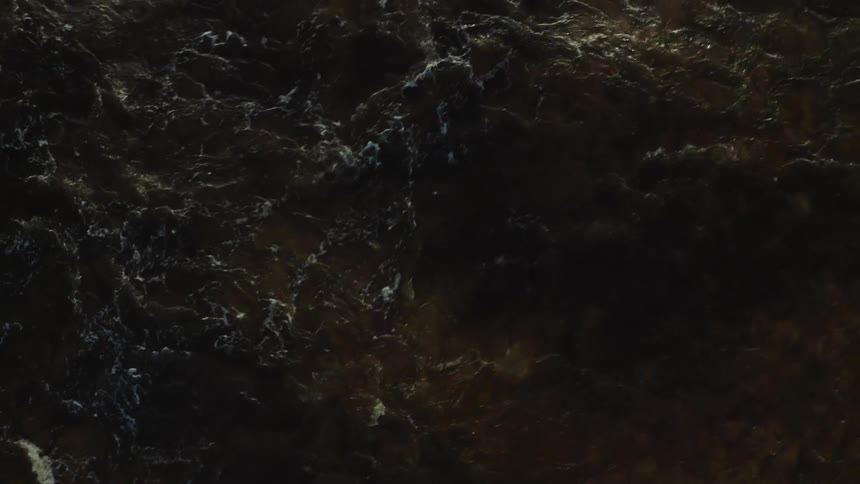 Dark current forms irregular waves and scattered foam seen from above