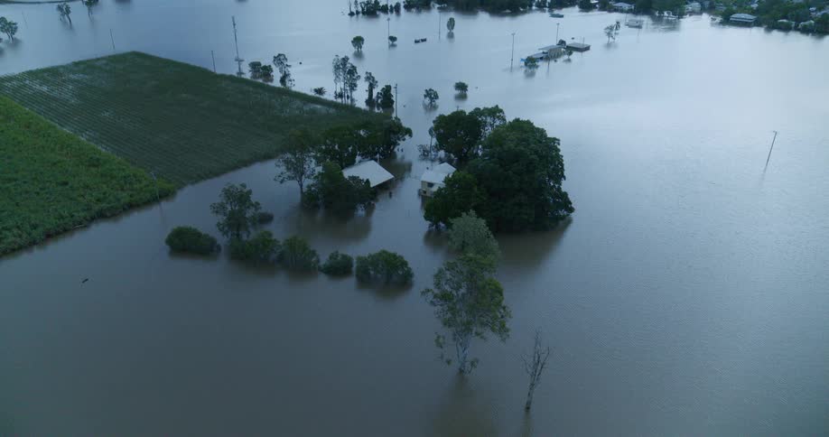 Flooded rural area shows agricultural fields trees and buildings partially submerged by water