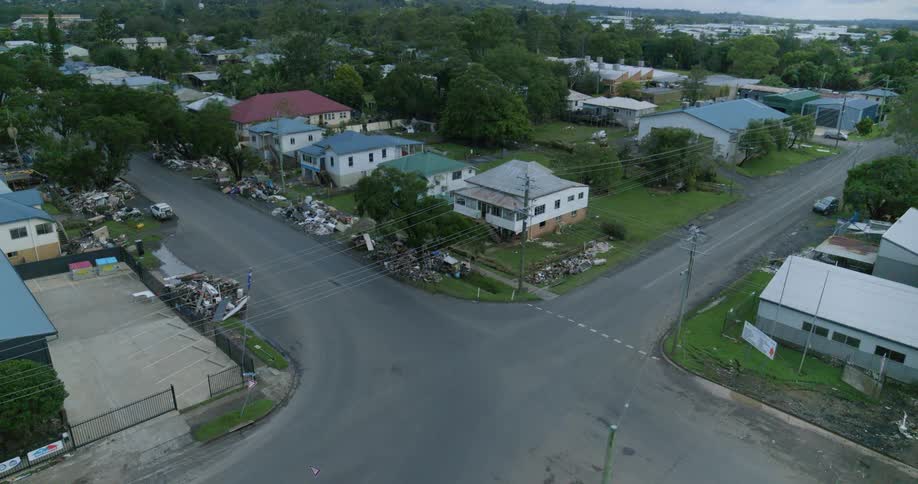 Vehicle drives through an intersection in a residential neighborhood lined with debris on a summer day