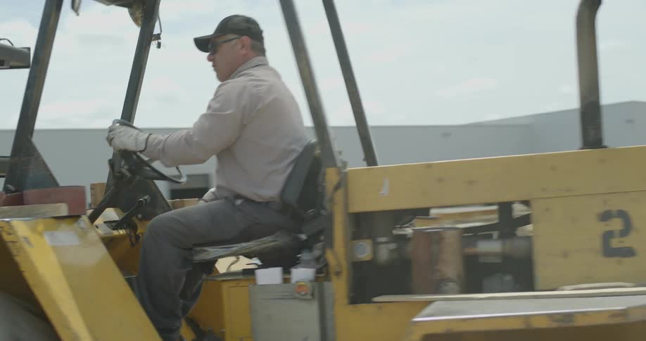 A man drives a construction vehicle on a lot