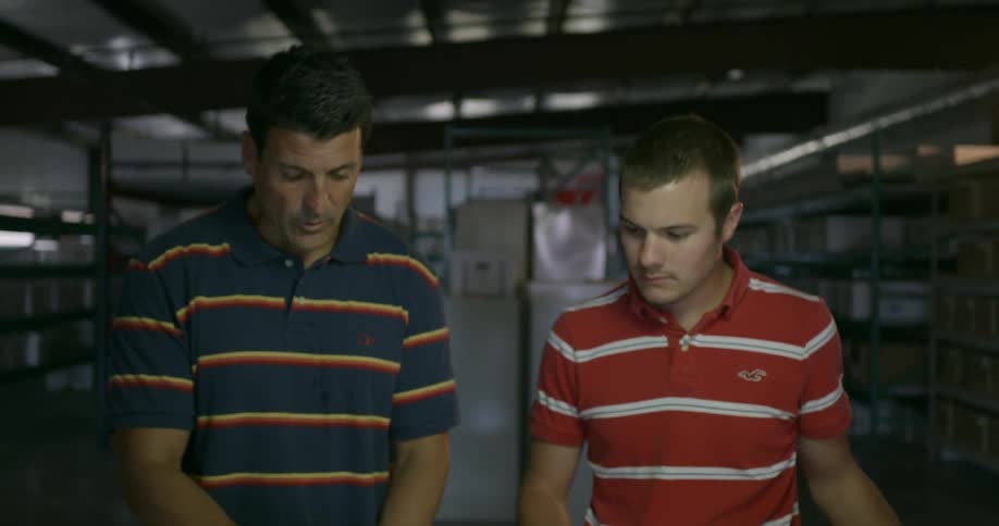 Two men stand looking at blueprints