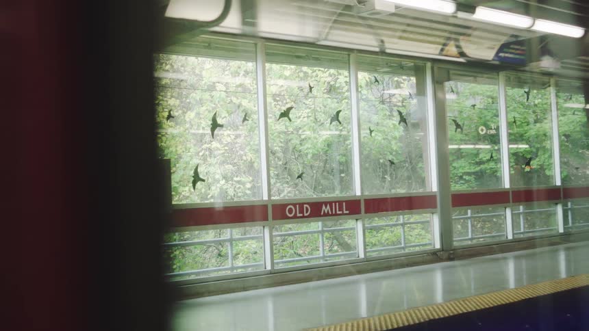 Train interior with empty seats reflected in window facing wooded area