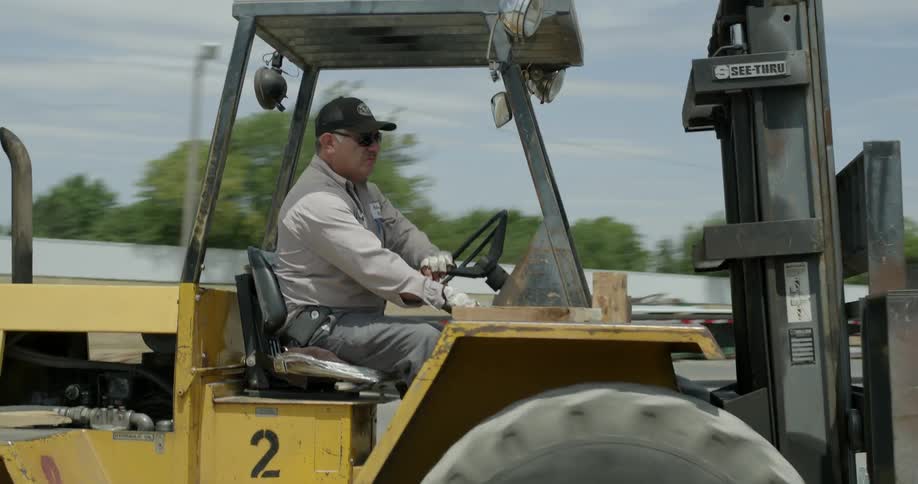 A man moves steel beams with a forklift
