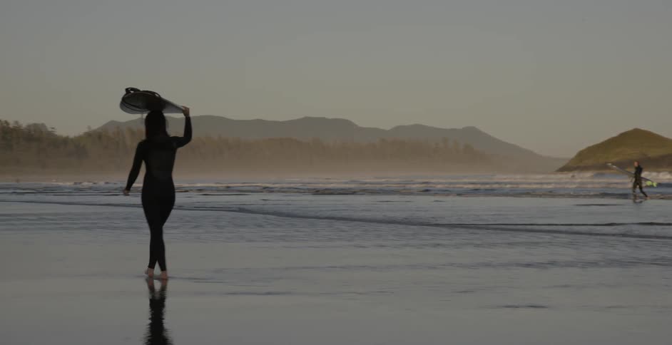 Surfers walk on a sandy beach