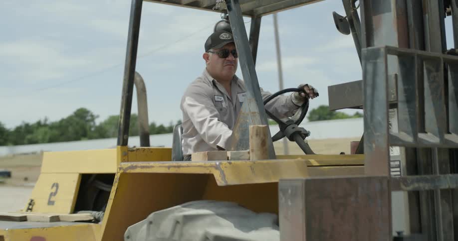 A middle-aged man is driving a forklift
