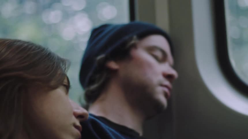A couple rests together leaning against each other on public transit