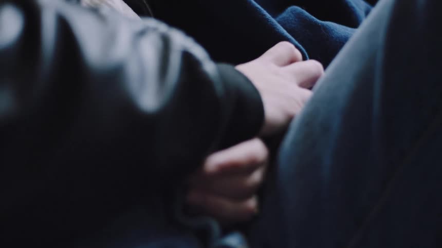 This video opens with a woman resting her head on a mans shoulder while riding likely on a bus or train and she closes her eyes to sleepthe shot then transitions to a closeup of their hands intertwined and resting on her lap suggesting a quiet