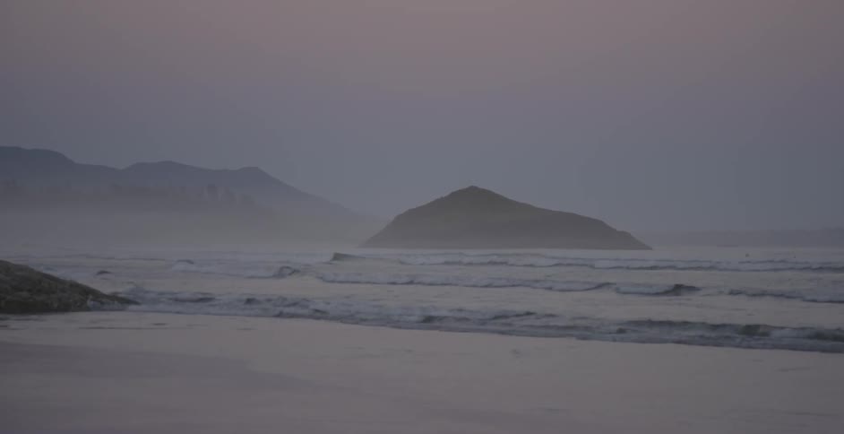 Ocean waves wash ashore a sandy beach at sunset