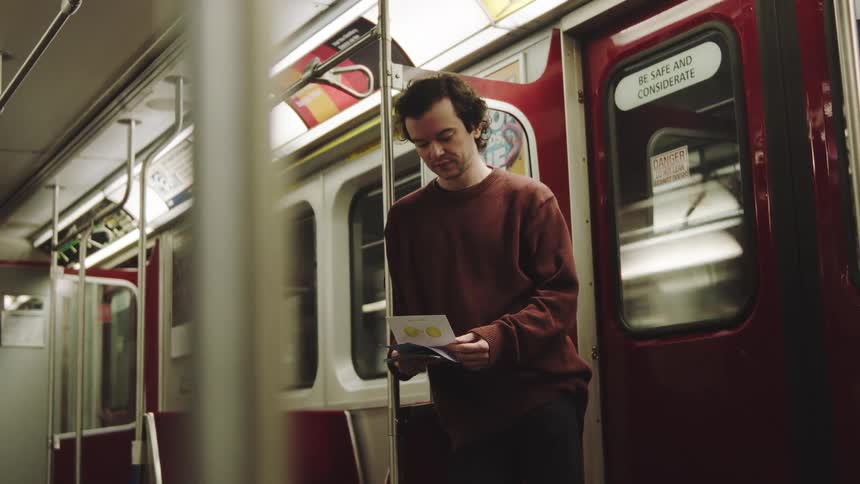 Man standing on a subway train looking through his wallet