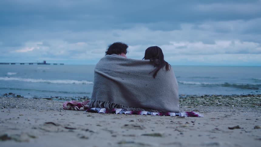 A man and woman hugging each other on the beach