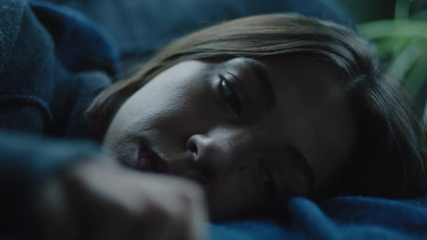A young woman lying in the belly of a man in an indoor setting both wearing blue sweaters