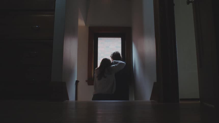 The woman looks out the window with a man
