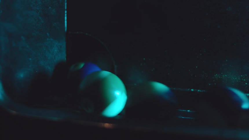 Pool balls roll down from a pool table with bright light reflecting on it